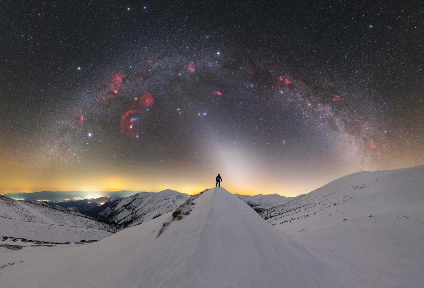 Winter Sky Over The Mountains. This image was shot with a H-alpha filter to peer through the dust of the Milky Way and reveal features invisible to the optical light spectrum, such as the nebulae (seen as red clouds)