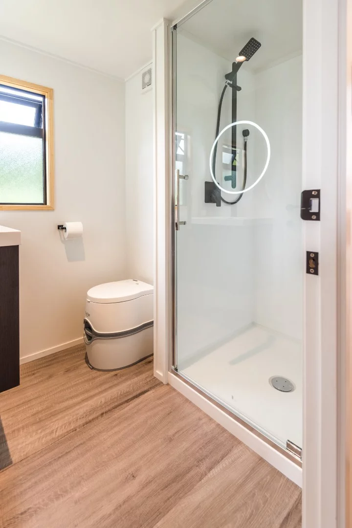 The Pohutukawa bathroom featuring a 900 × 900 mm (35 x35 in) shower, vanity, toilet and heated towel rack