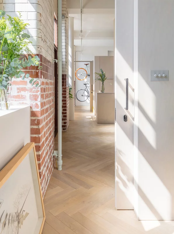Exposed brick work is contrasted by the warm lines of the birch pods and clean white walls
