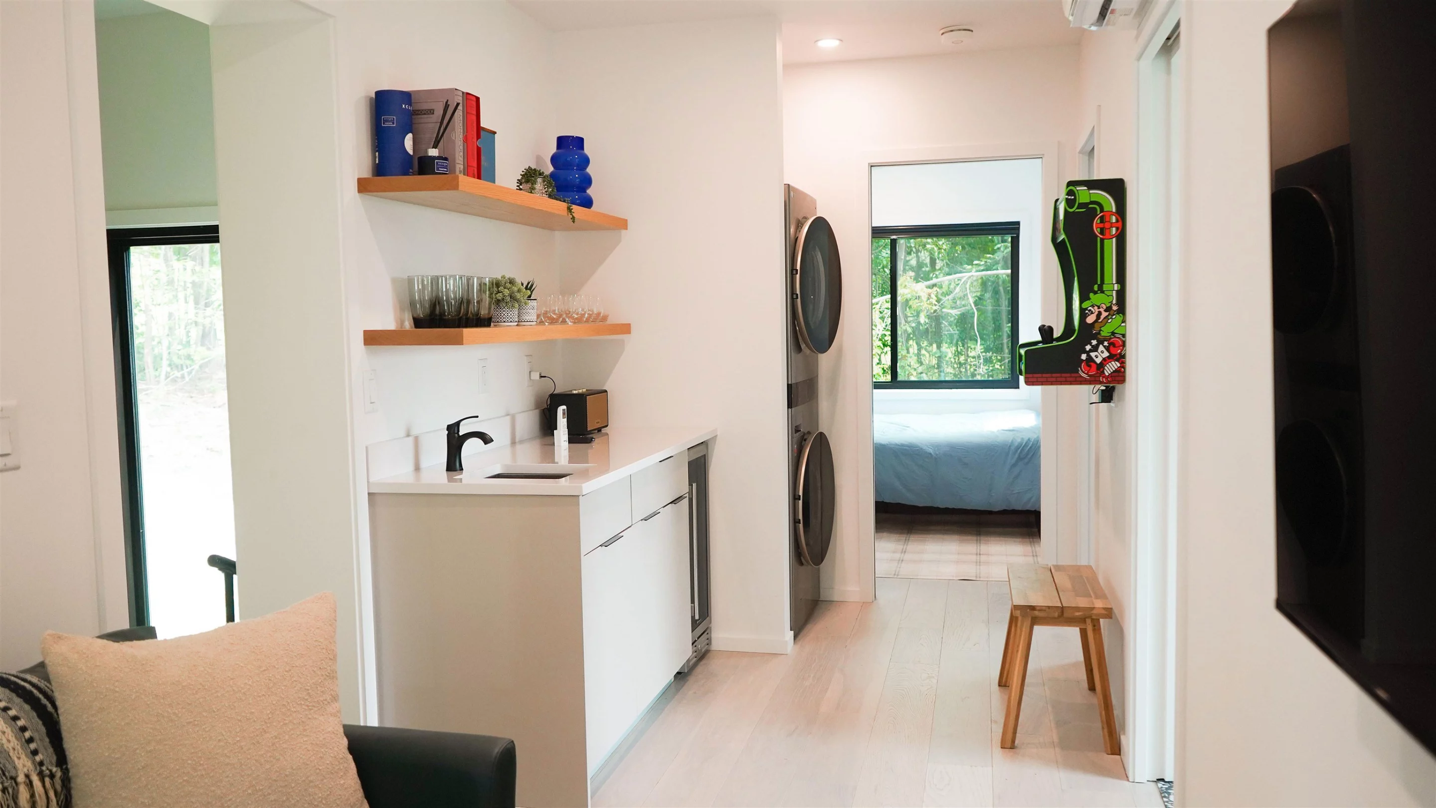 The Vermont Villa includes a secondary living space with a sofa and a wall-mounted video games system, along with a wash area that includes a sink and a stacked washer/dryer