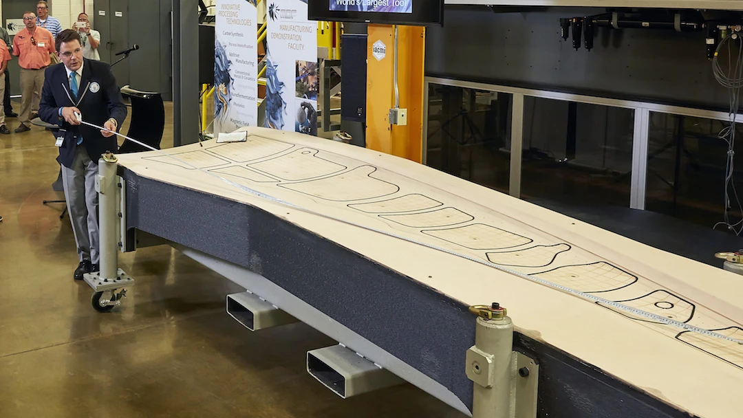Guinness World Records judge Michael Empric measures ORNL's 3D printed trim-and-drill tool, which is now the world's largest solid 3D printed item