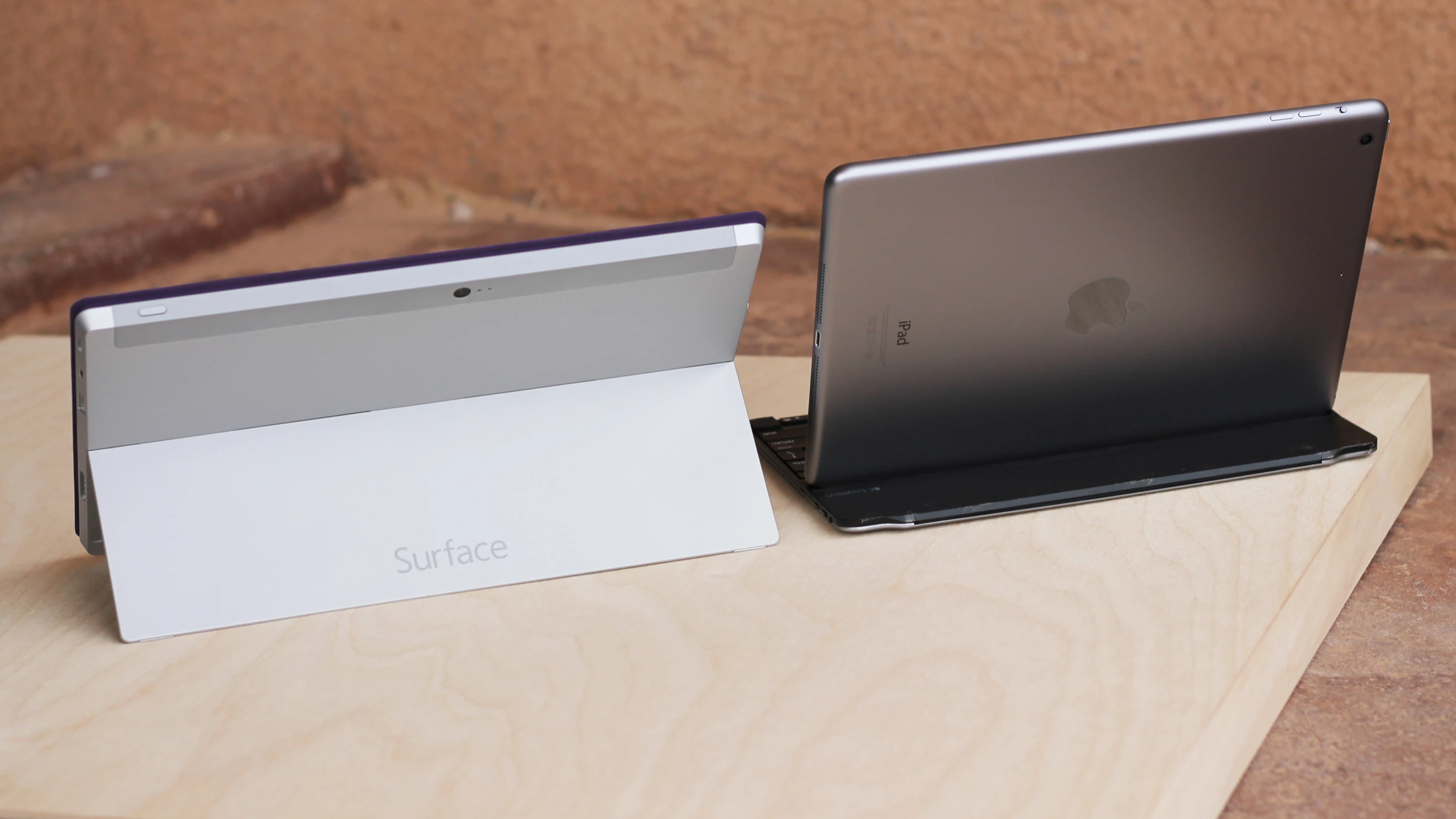 Backs of the Surface 2 and iPad Air, propped up in faux laptop mode