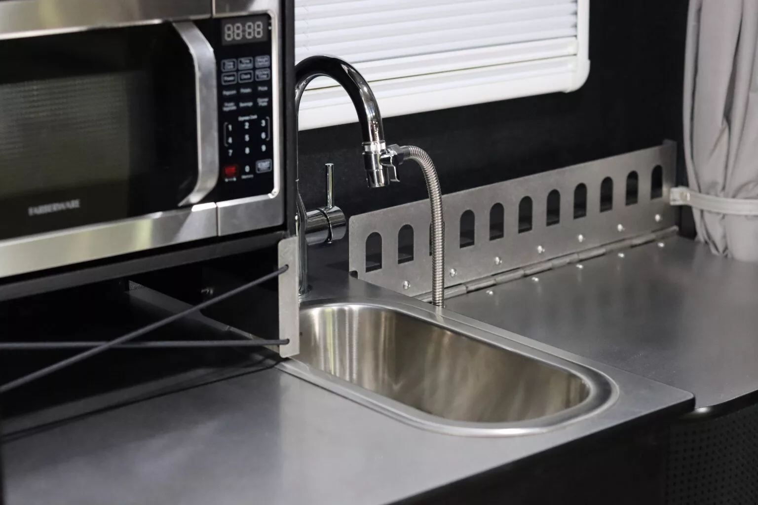 The kitchen sink has a narrow oval basin and an attached shower/dish sprayer