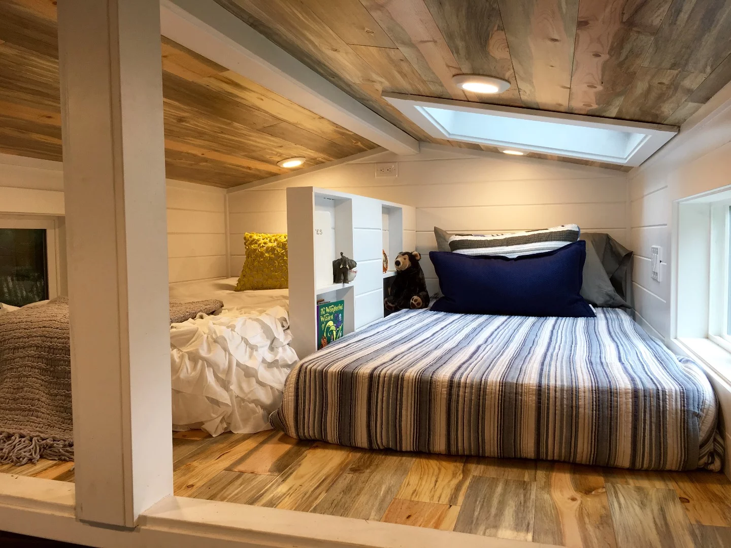The kids bedroom in the Rocky Mountain Tiny Home is divided in two by bookcase storage
