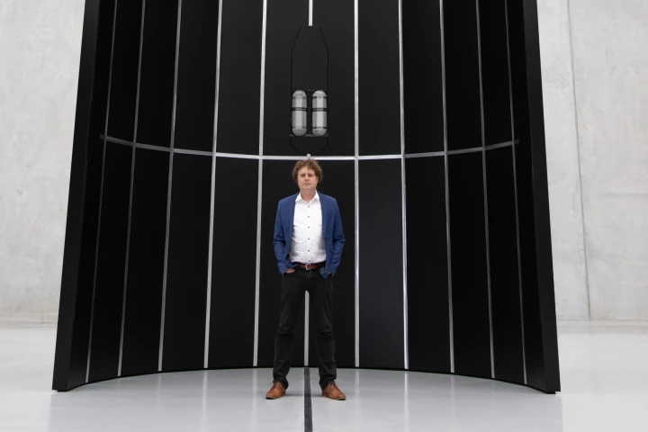 Rocket Lab CEO Peter Beck stands in front of the payload fairing for the company's Neutron rocket