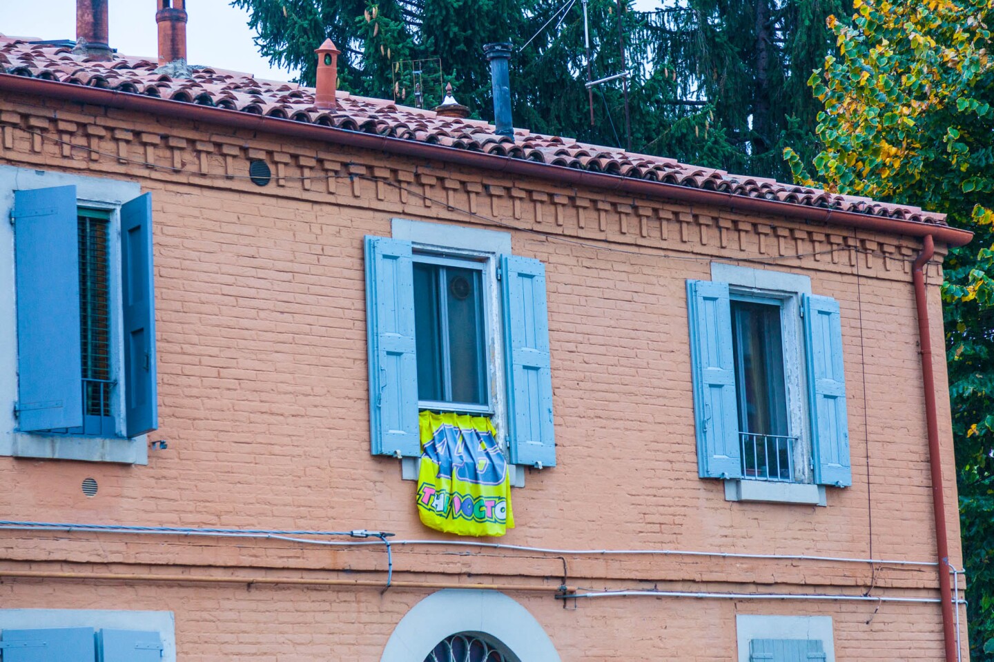 Directly across the road from the factory gate, a defiant Rossi fan hangs a #46 flag.