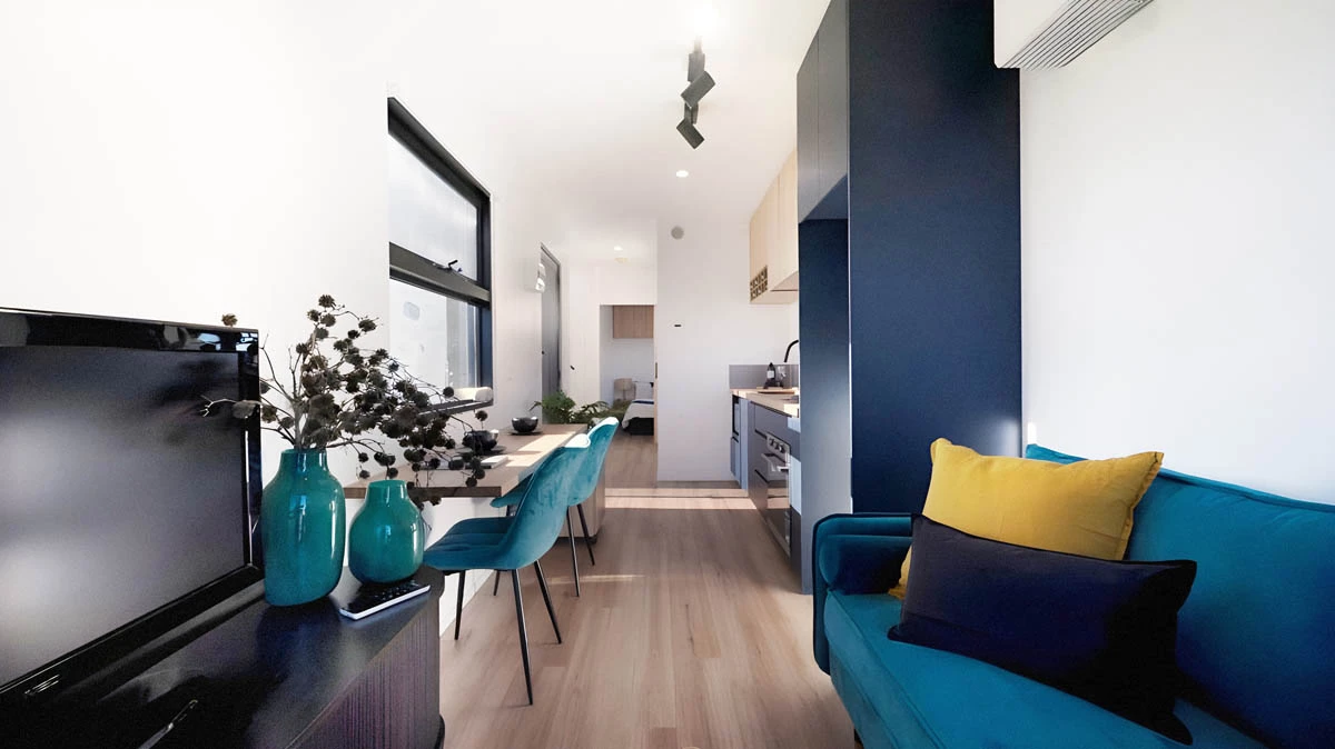 The Mark T's living room features a sofa, entertainment center, and large glass doors that open it up to the outside