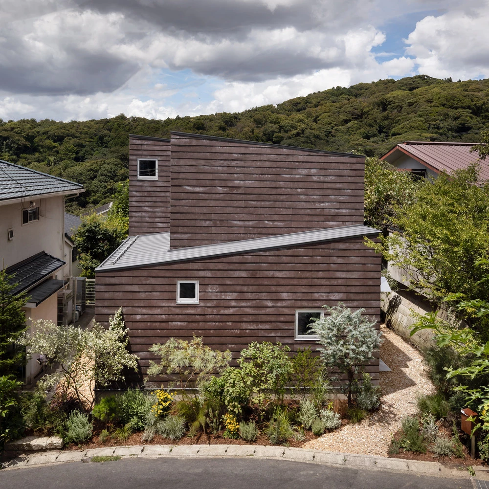 Cat Tree House consists of two L-shaped volumes with slanted tin roofs of opposing angles