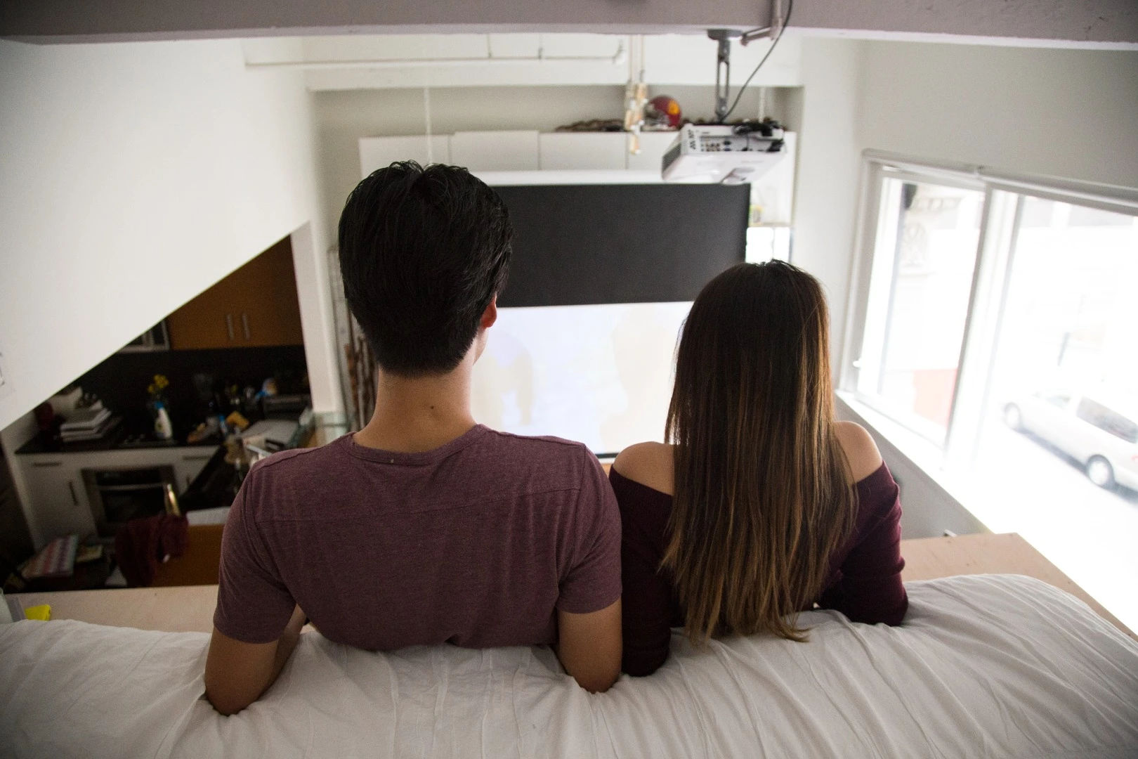 A projector is used to display content on a wall opposite the master sleeping space