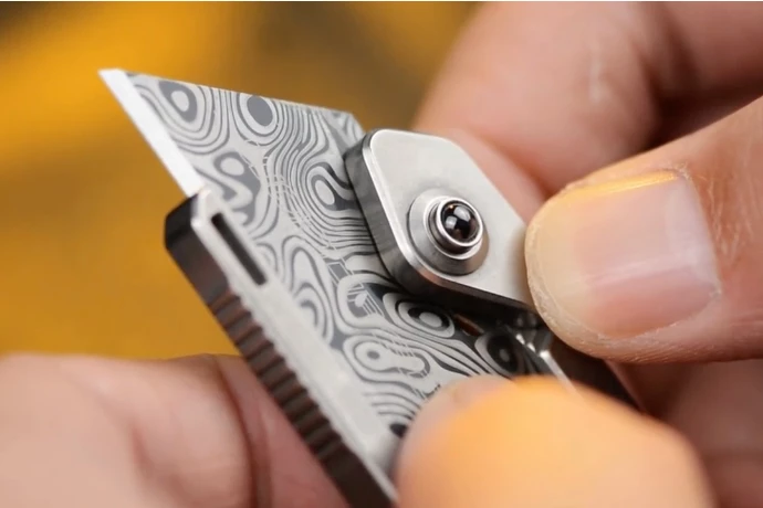 Pressing the ceramic bead compresses the spring-loaded locking pin, allowing the blade to slide through