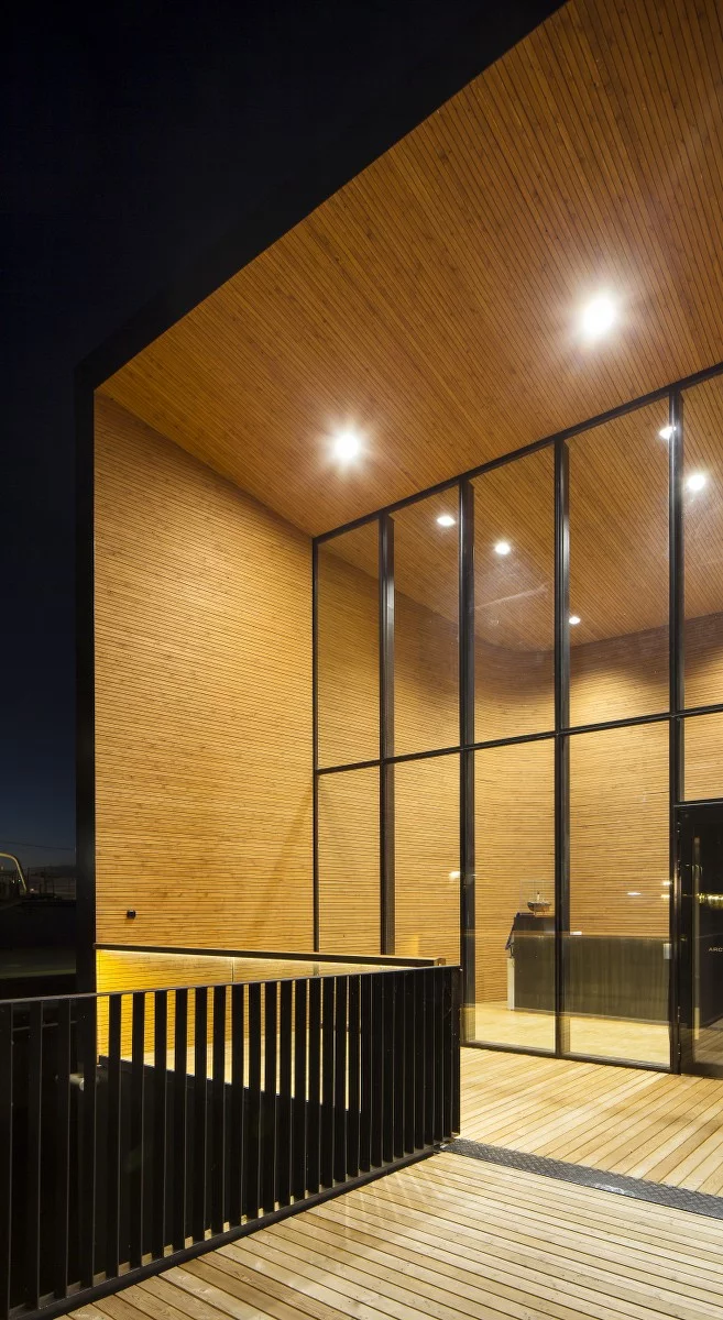 The building's cold and rigid exterior is in stark contrast to its warm interior, which boasts soft curves and an abundance of wood