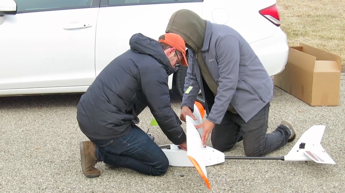 Research team members mount the battery wing on the drone