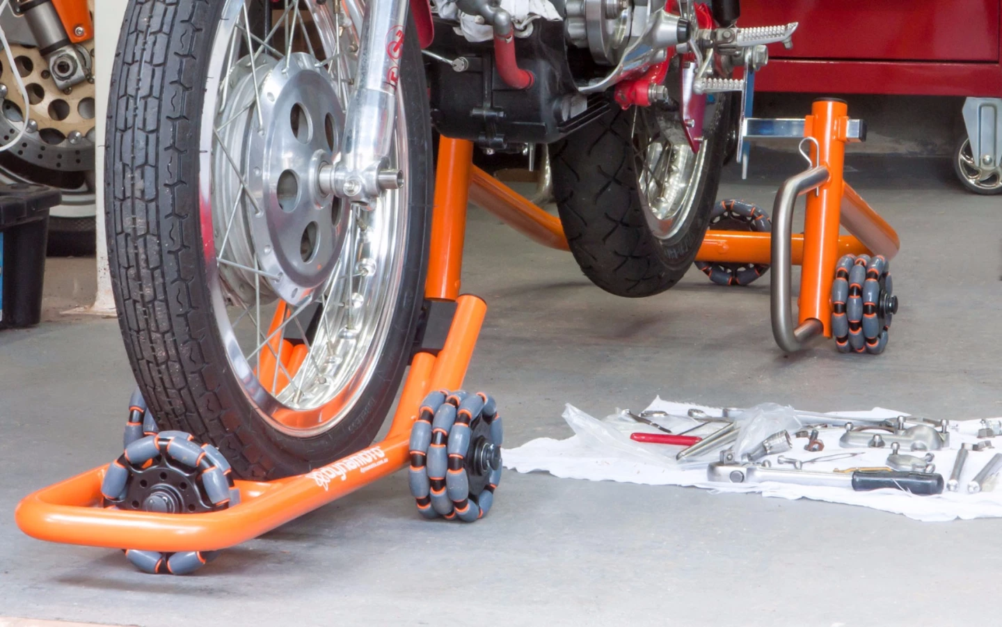 Dynamoto's front stand scoots under the front wheel to lift the bike without the need for spools