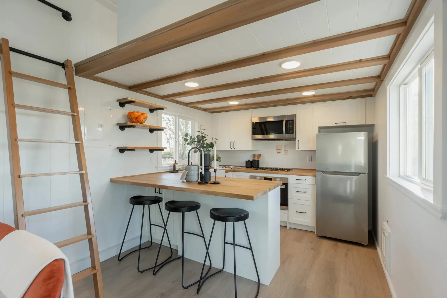 The Ventura Park Model Tiny Home's kitchen includes a fridge/freezer, farmhouse-style sink, oven and microwave