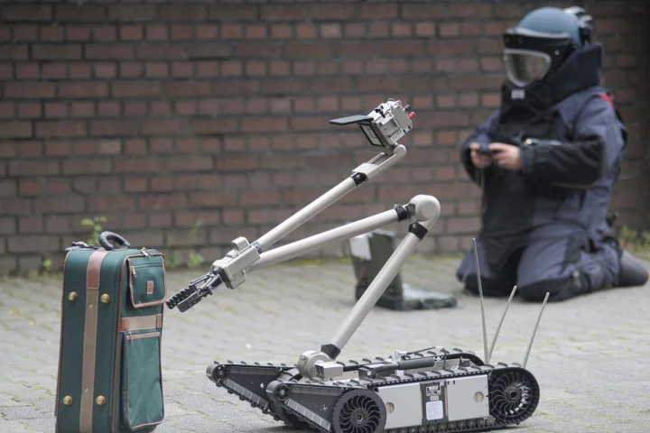 Emergency personnel defuse a suitcase bomb with the robot's aid
