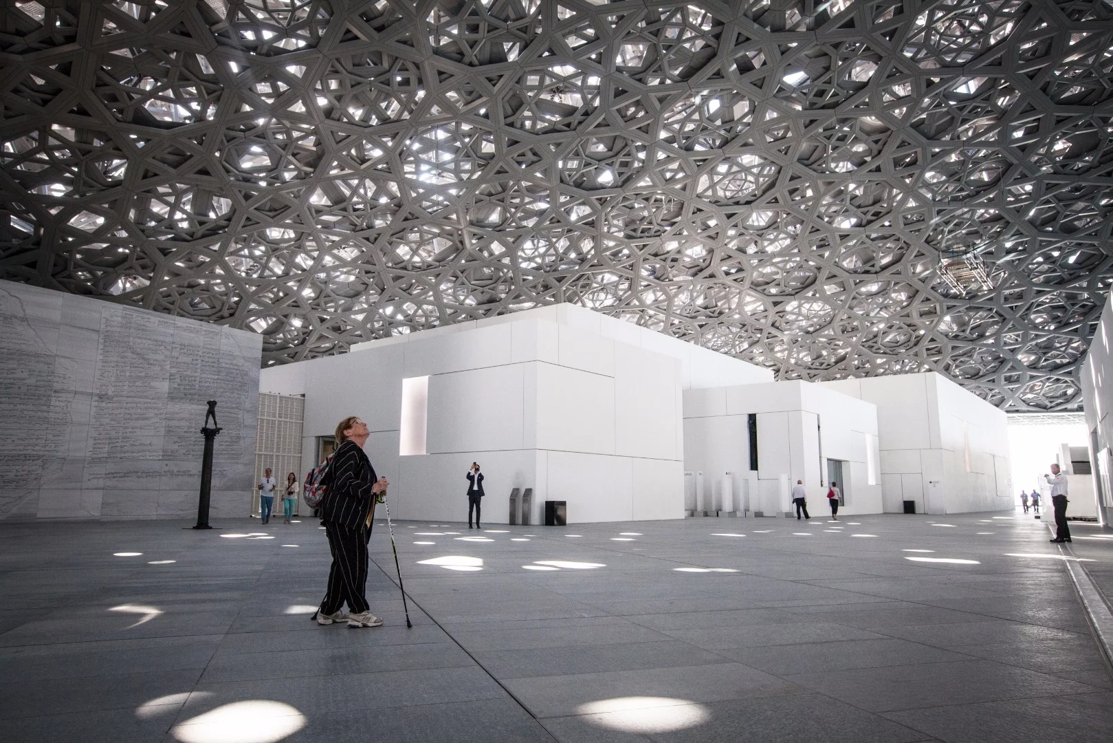 A visitor peers up towards the dome roofing at the Louvre Abu Dhabi