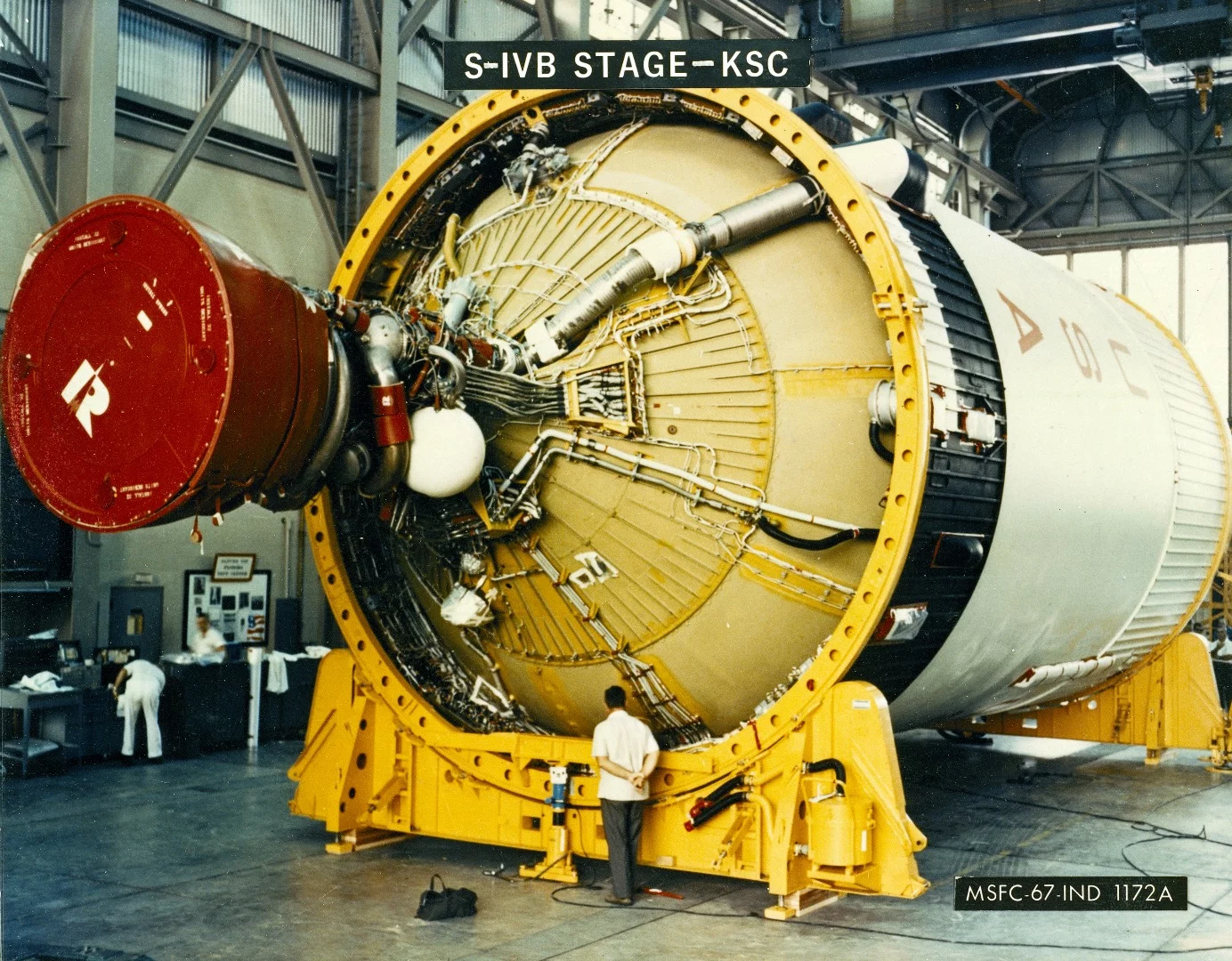 A NASA technician is dwarfed by the gigantic Third Stage (S-IVB) as it rests on supports in a facility at KSC