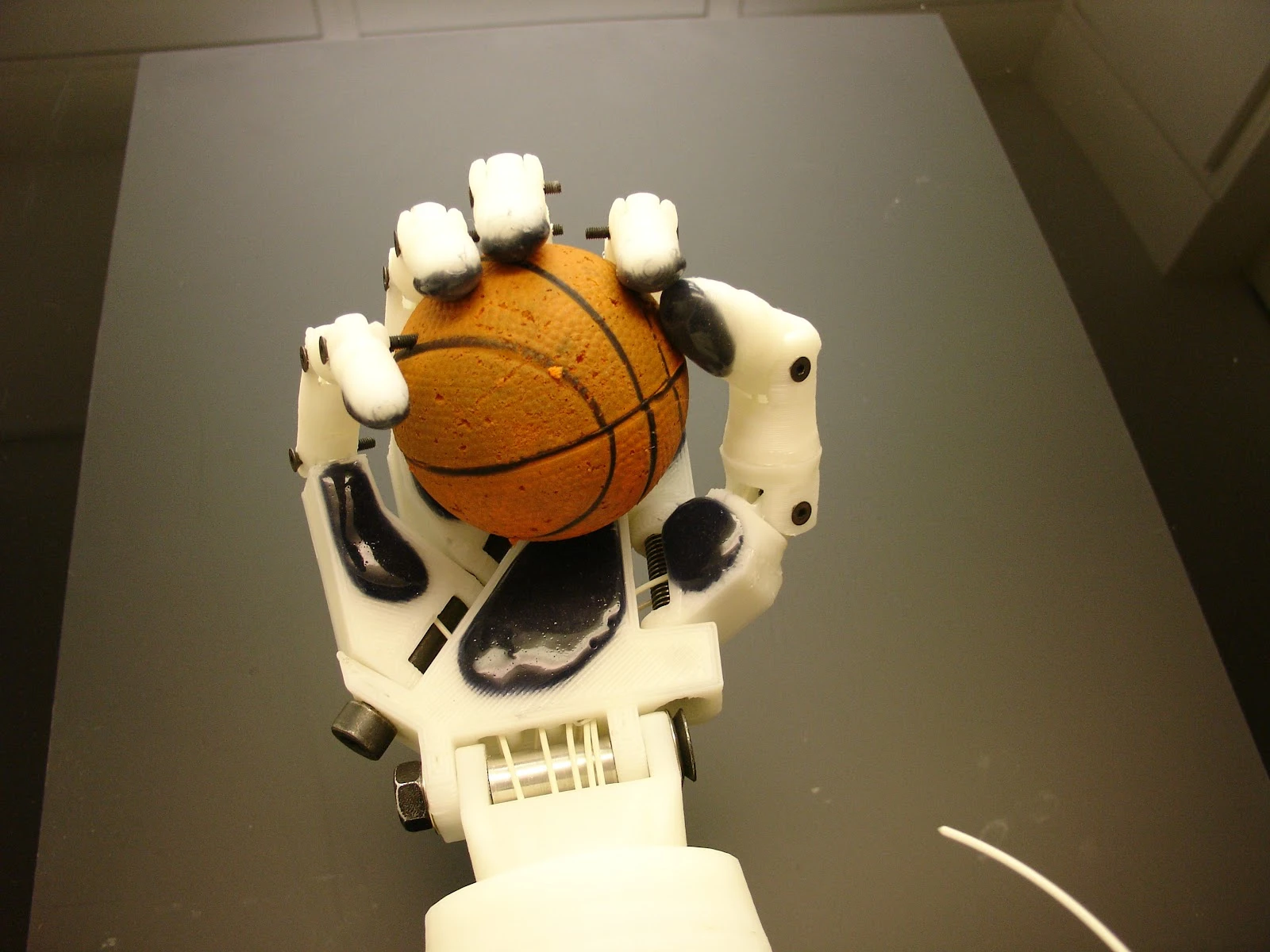 A close-up of InMoov's hand holding a miniature basketball