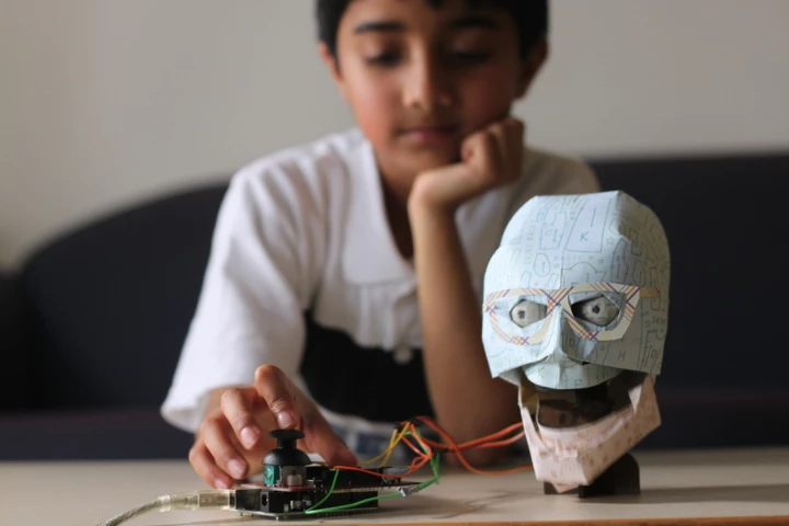 TJ* (seen here with an optional paper "skin") is a robotic human head that is controlled in real time or in response to code, provided by the user