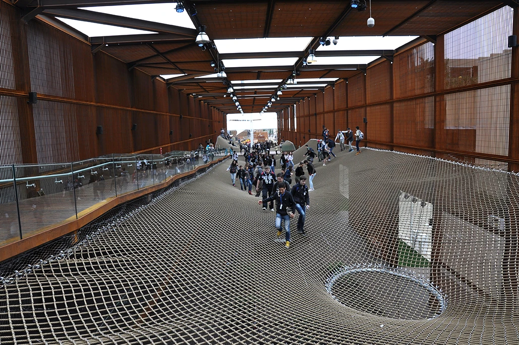 Visitors make their way up and over the massive nets and around into a large indoor exhibition space