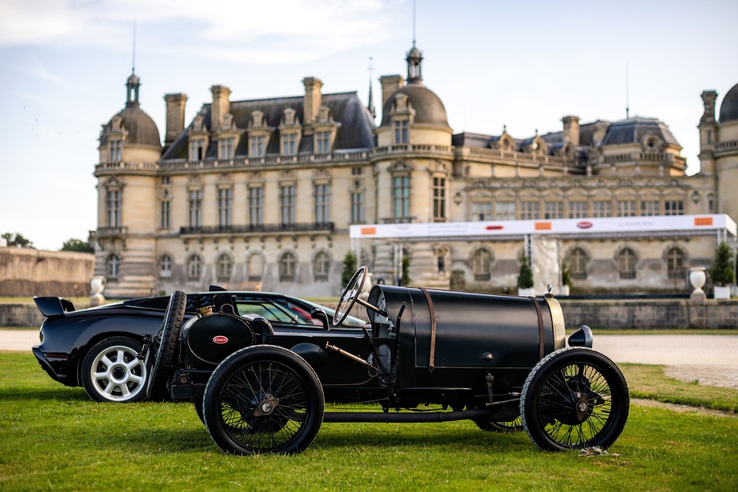 Bugattis, 100 years apart, side by side. In the foreground is a 1919 Type 13 and in the background is the most expensive new car in the world, Bugatti's $12.3 million 2019 La Voiture Noire.