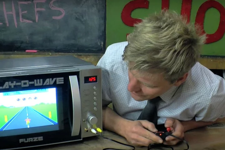 Colin Furze plays an old school video game while waiting for his meal to cook