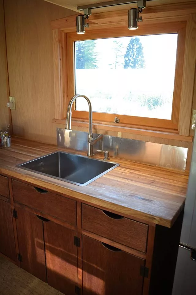 The kitchen features a sink and tap, a small range oven with five burners and two ovens, a washing machine, and an energy-efficeint fridge