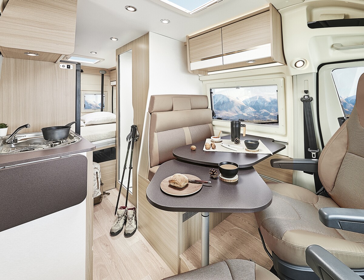 The interior is a classic layout with driver-side dining area and bathroom, passenger-side kitchen, and rear bedroom