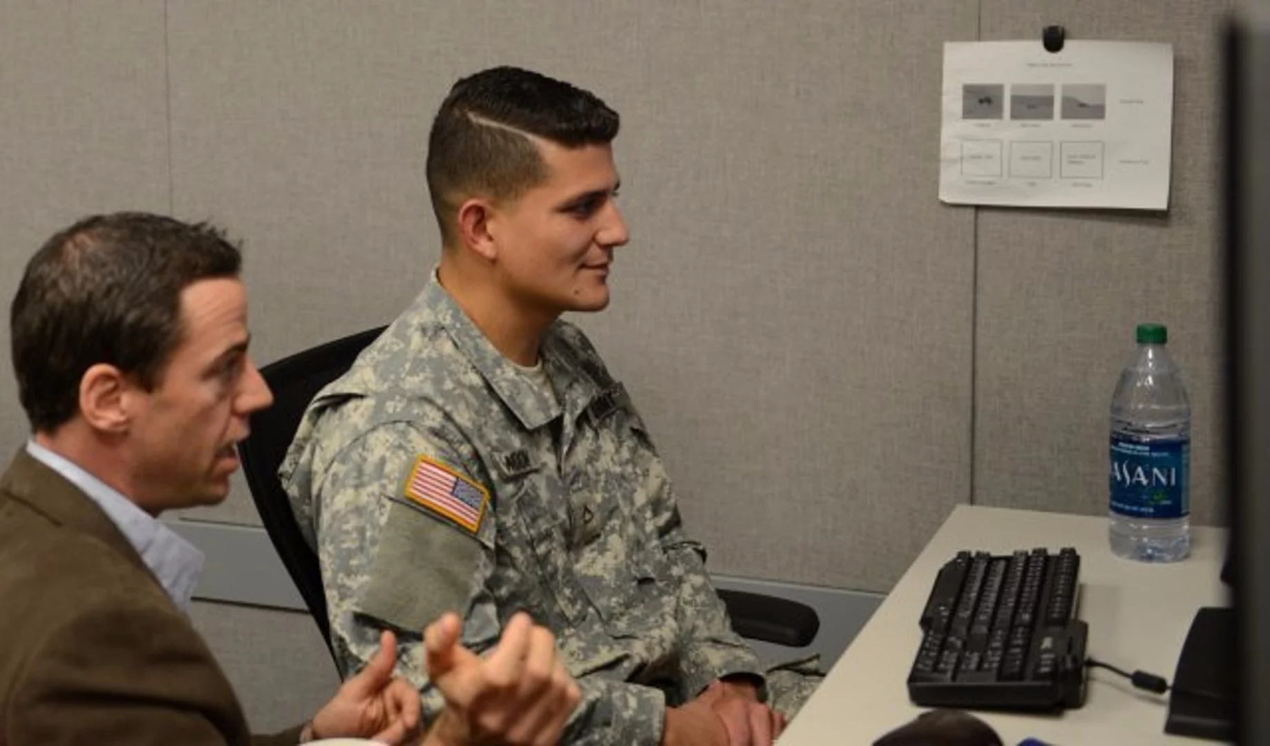 Anthony Ries instructs Pfc. Kenneth Blandon on how to play a computer game that uses eye-tracking technology