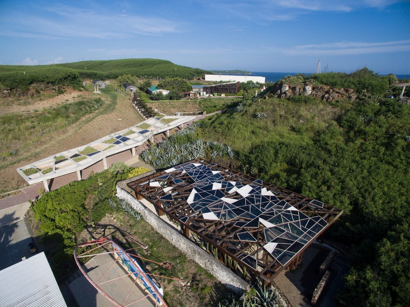 The Penghu Qingwan Cactus Park's basaltic-based greenhouse is roofed in a mosaic of panels to let light in, all framed in teak