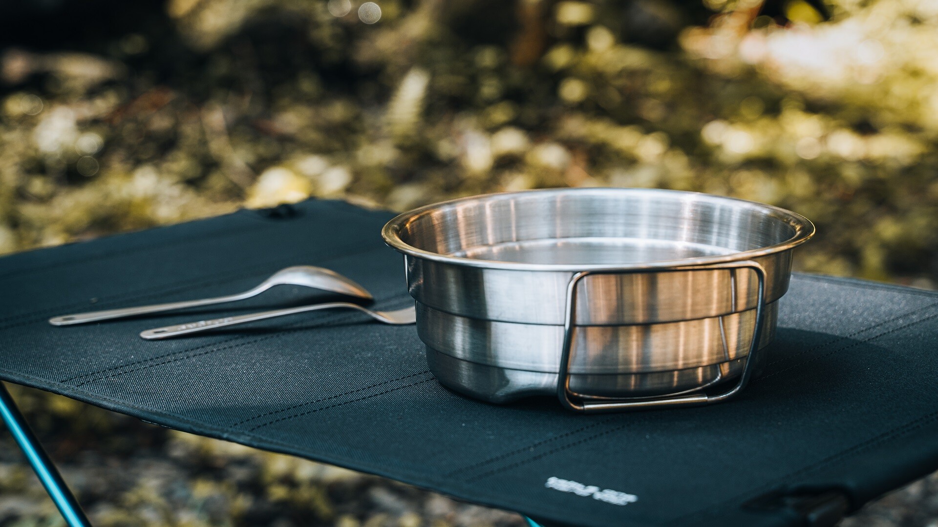 Collapsible steel camping pot compacts into a thin disc for easy carry