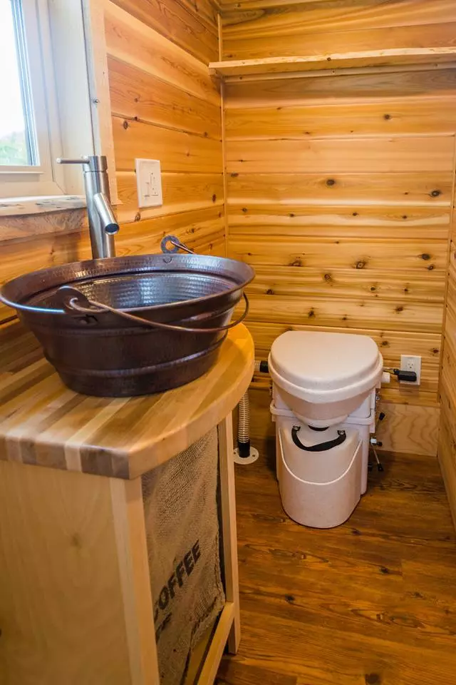 The bathroom in Davis's 22 ft Off-Grid Tiny Home has a stainless steel shower surround, copper pail sink, and composting toilet