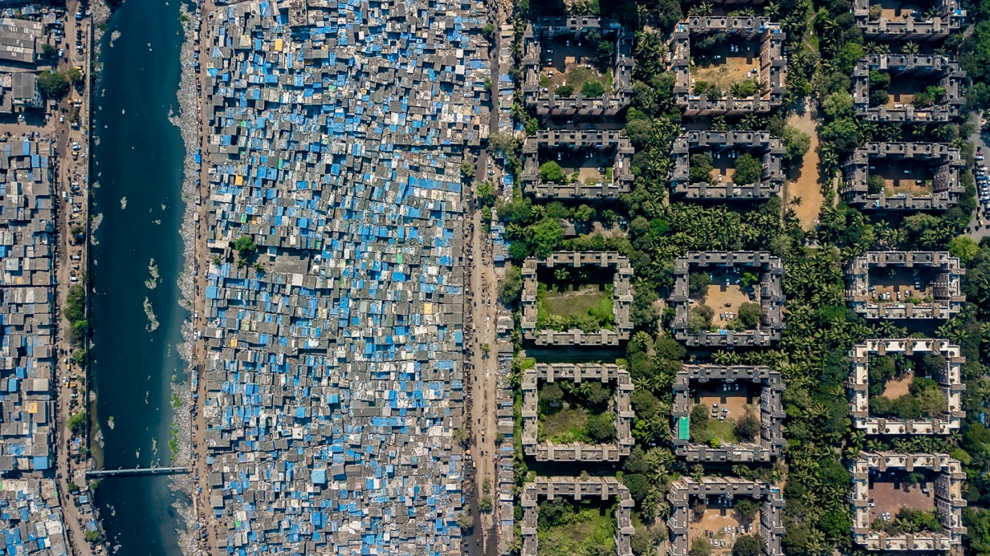 Very tightly packed homes make up this slum in Mumbai, India, alongside greener pastures
