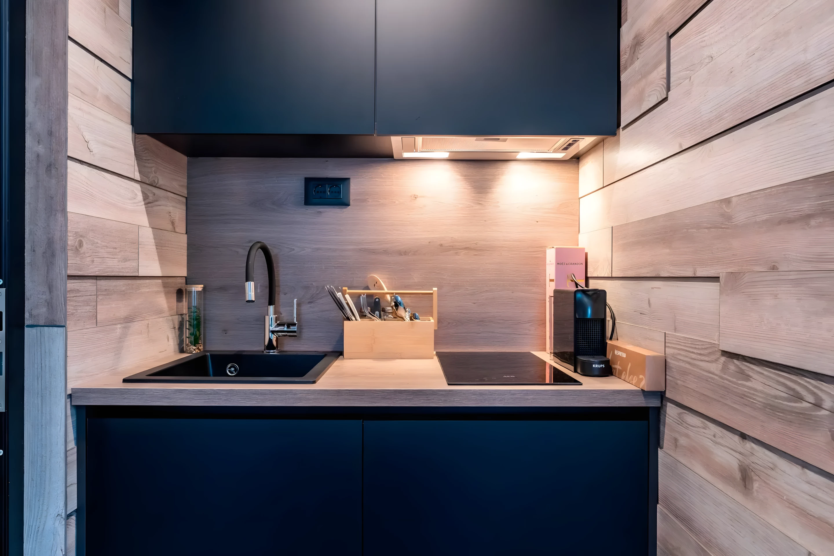The DQ Tower's kitchen is small and includes an induction cooktop, a small fridge, and a sink