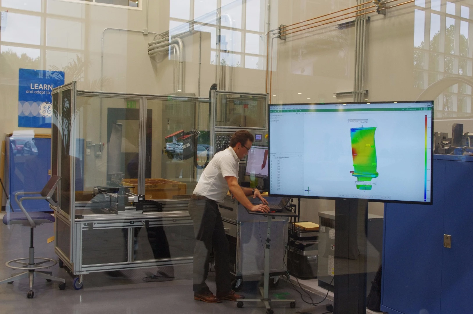 The readout on the screen on the right shows the results of a scan, with the yellow and red areas showing where the part was smaller than it was meant to be, and the green and blue showing where it was bigger