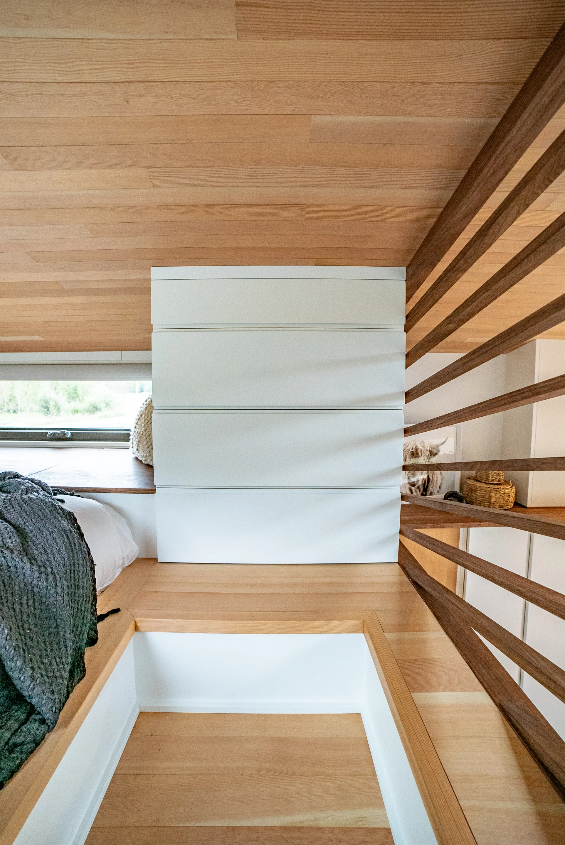 The Trahan Tiny House's loft bedroom includes a lowered platform so that the owner can stand upright in the small space