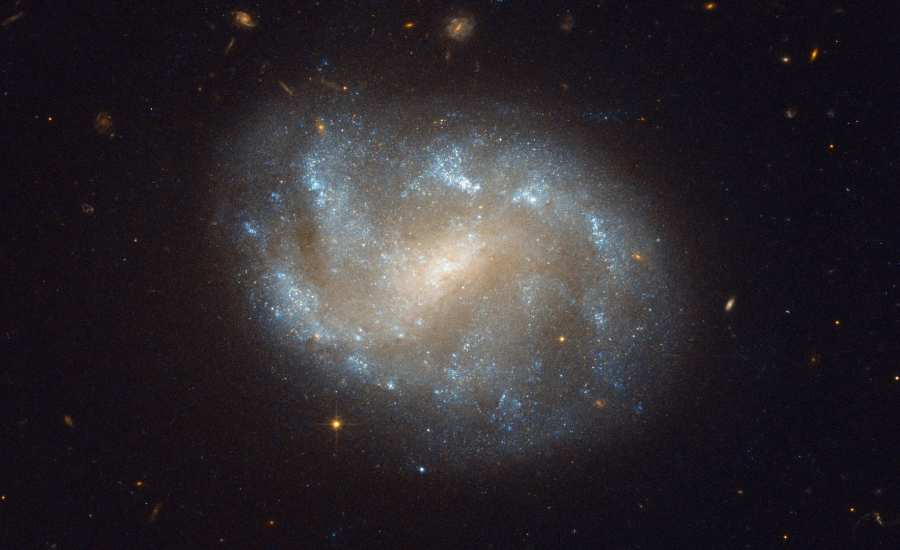 NGC 1483 is a barred spiral galaxy located in the southern constellation of Dorado — the dolphinfish in Spanish. The nebulous galaxy features a bright central bulge and diffuse arms with distinct star-forming regions. In the background, many other distant galaxies can be seen