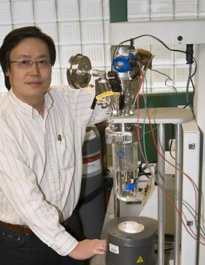 Andy Hong and a chemical reactor similar to the one used to develop and test a new method for removing pollutants, including oil sheen, from water and, in some cases, soil