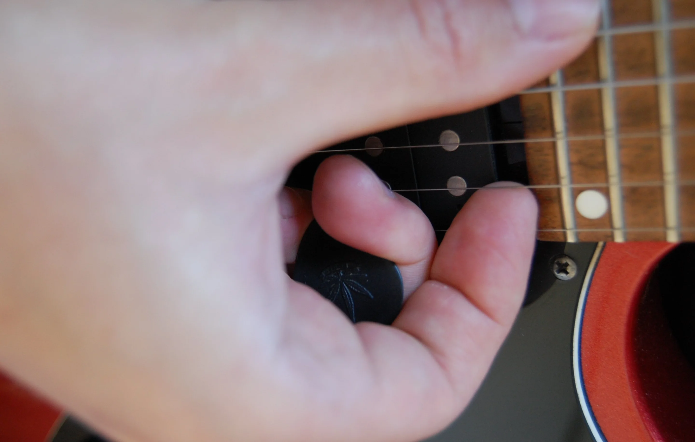 Players who have trouble with pick palming (shown here) for occasional fingerstyle playing might find the PicBand system helpful