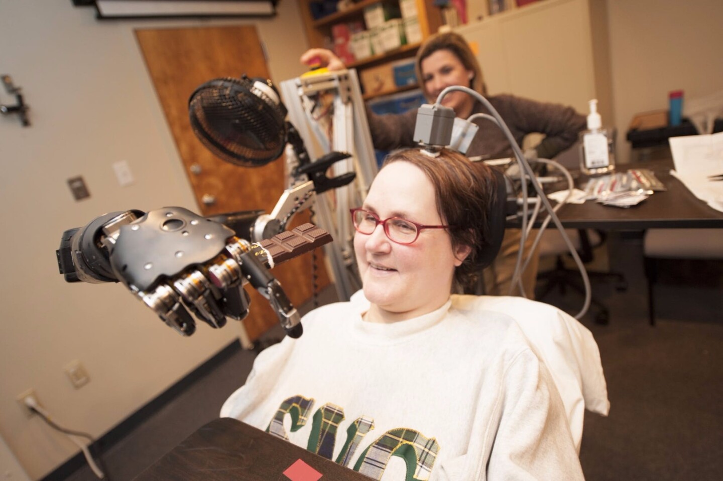 A quadriplegic women takes a bite of chocolate using a robotic arm