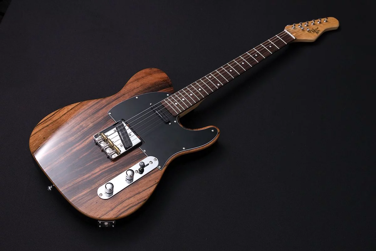 The guitar has an alder body with a striped ebony top and maple binding, with a maple neck bolted on