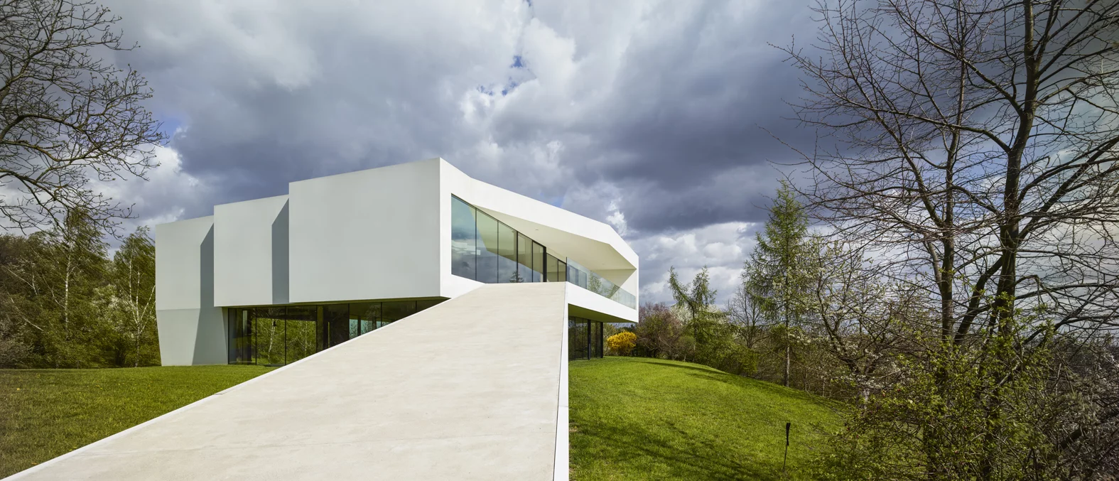 The By The Way House features a sloping walkway that descends to the garden and riverbank