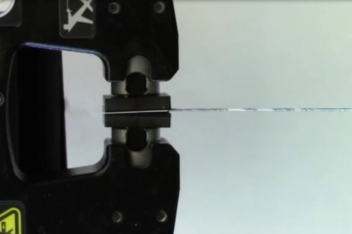 A sample of the fiber is stretched in the lab – the silver sections are the gallium core, which shows numerous breaks