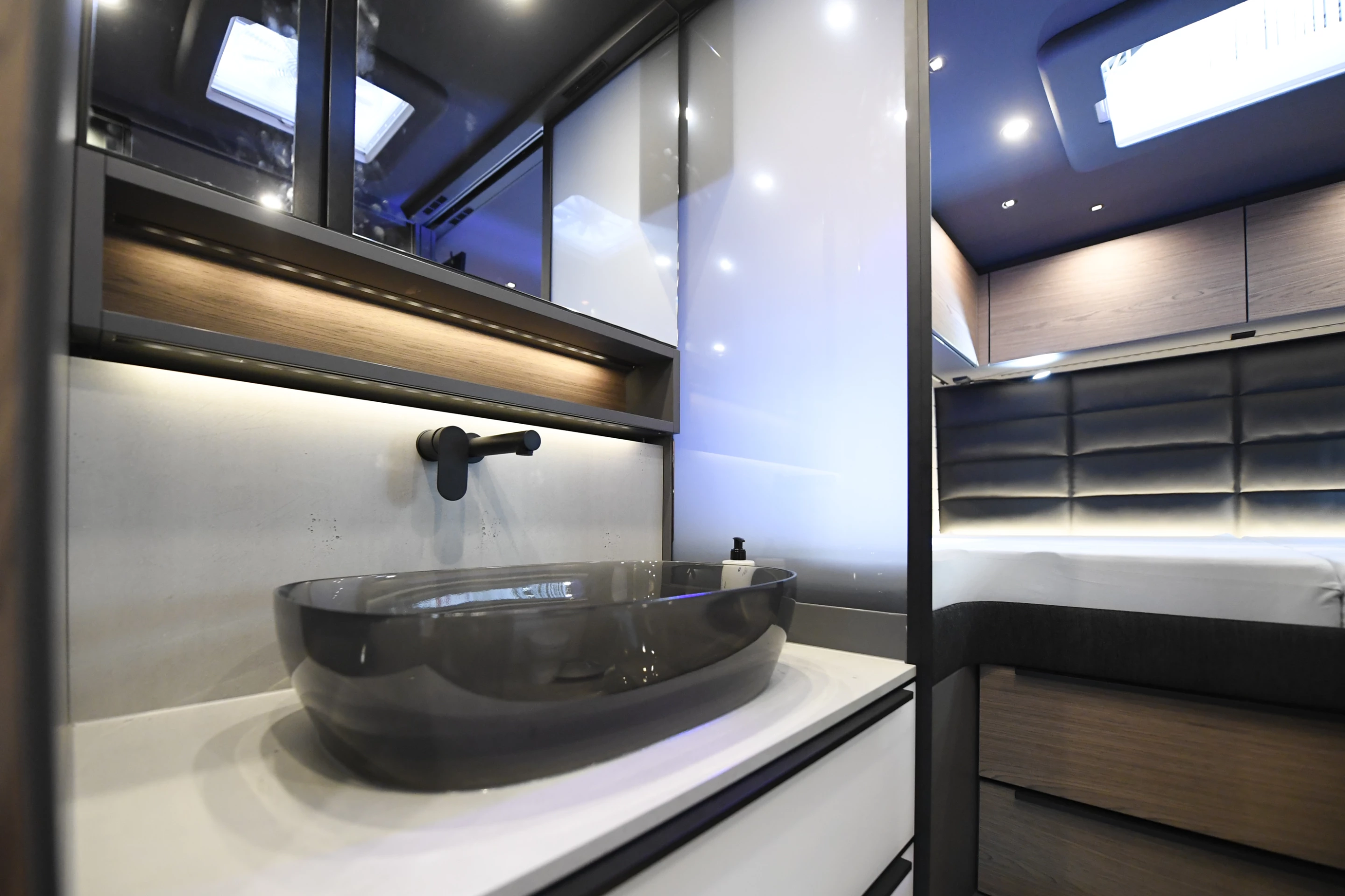 The bathroom sink is located in the hall opposite the toilet room, inside the wall console that also includes a wardrobe and refrigerator