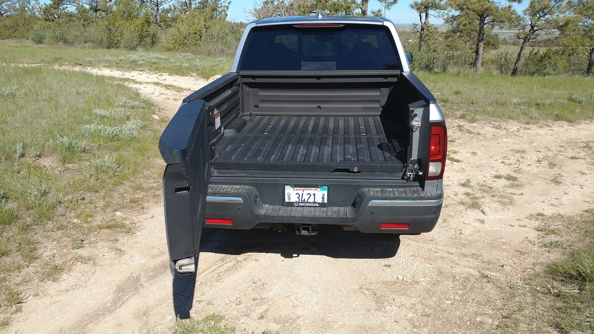 Grasping the secondary latch handle (to the right, near the tail lamp) swings the tailgate of the 2017 Honda Ridgeline to the left for easier loading of bulky items