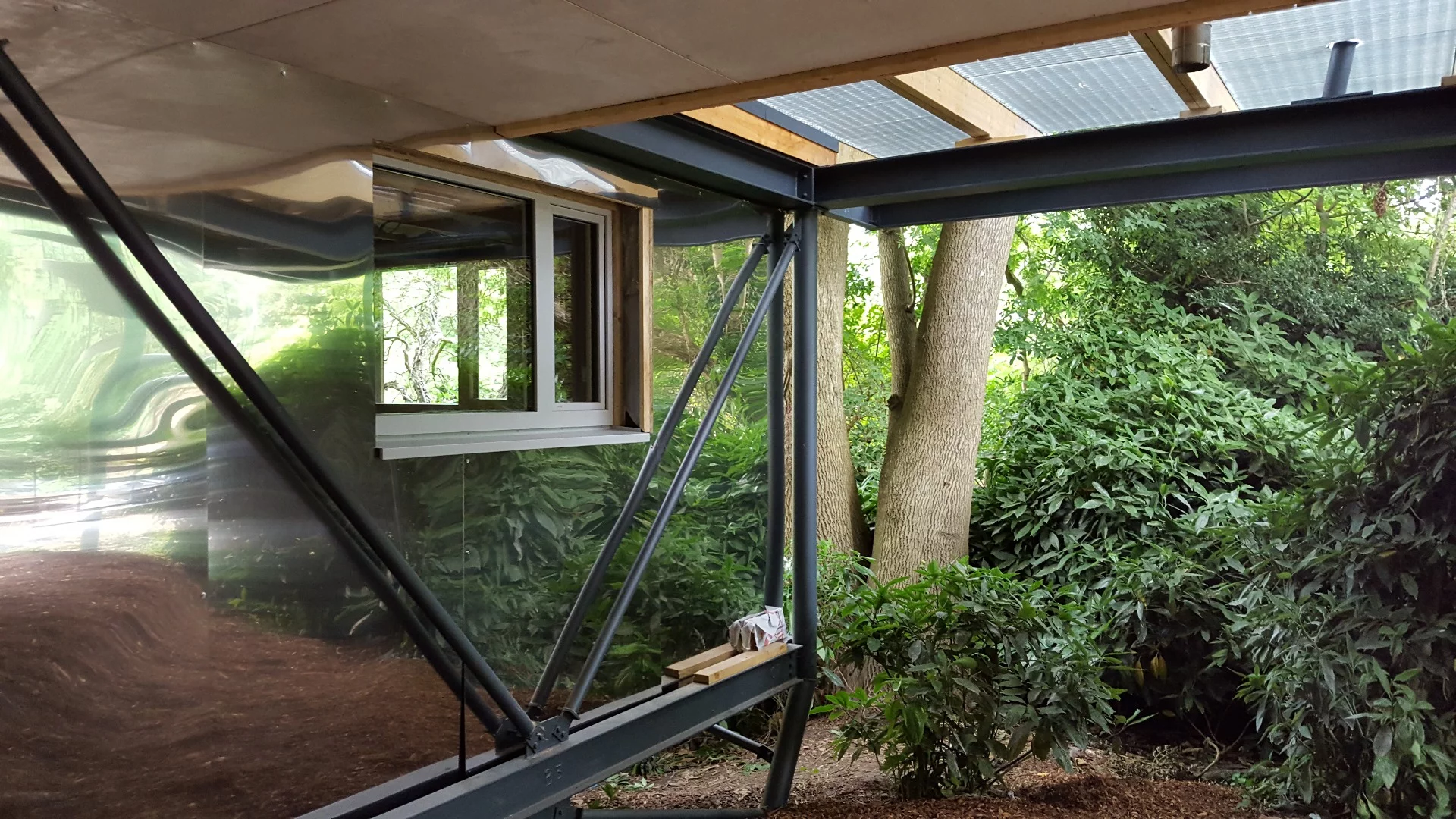 The base of the home is clad with polished stainless steel to reflect the trees and surrounding landscape