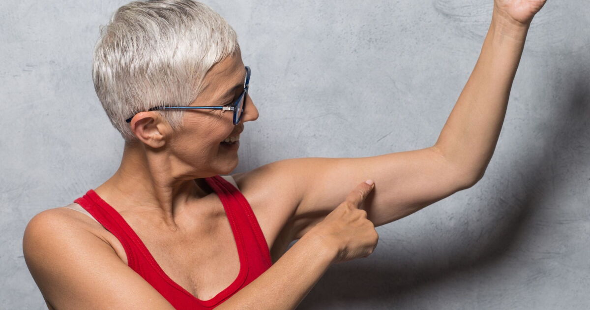 Grey haired woman pointing at her arm