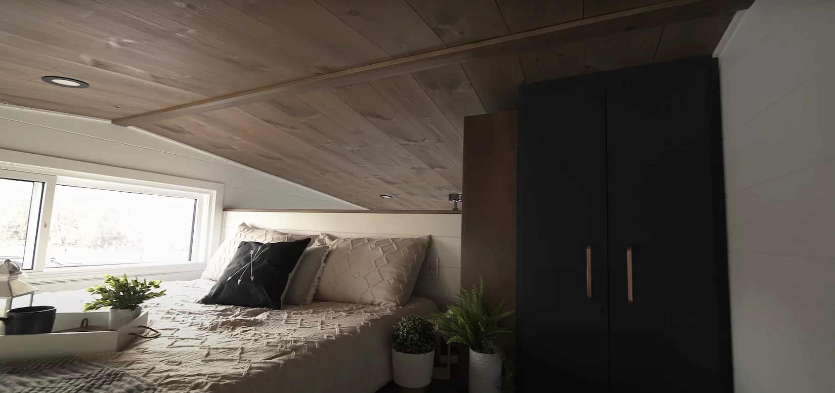 The 2024 Noyer XL's upstairs bedroom is a typical tiny house-style space with a low ceiling, plus a little storage space