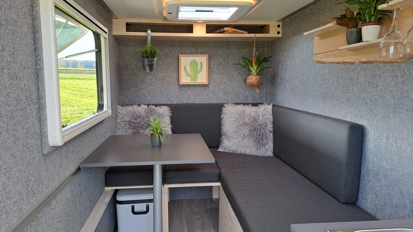 The folding stowaway table and shelving are available optionally; the felt walls and sofa-bed are part of the standard base package