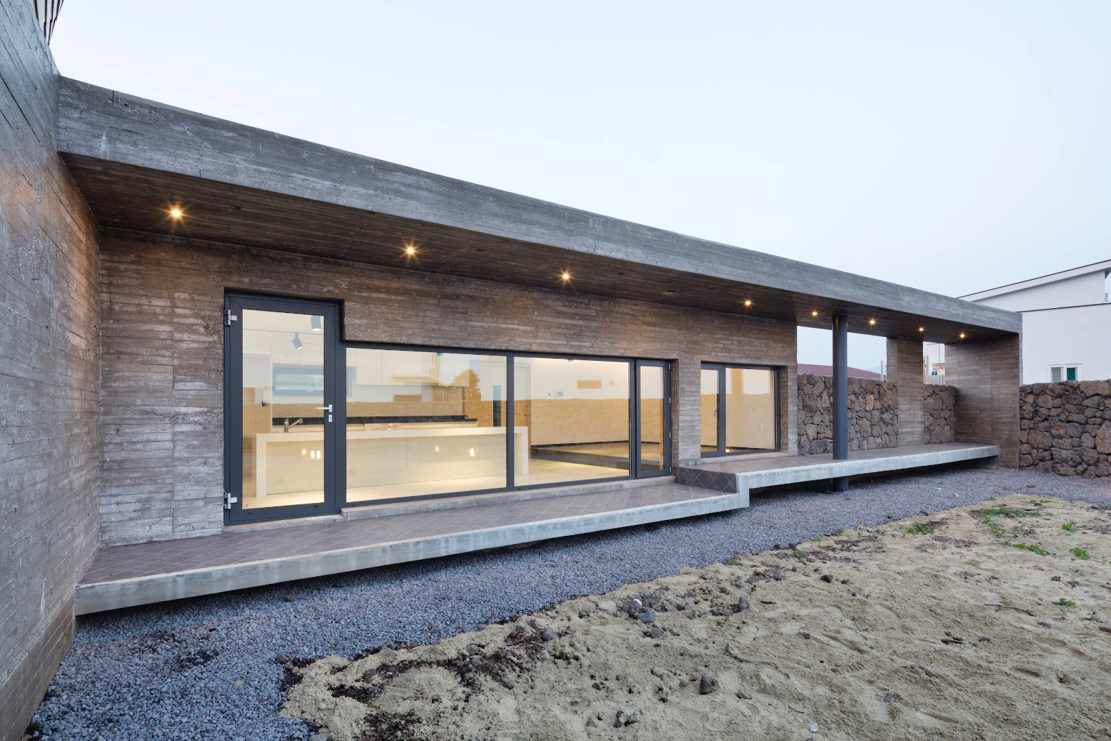 The Wind House features large windows and volcanic rock walls